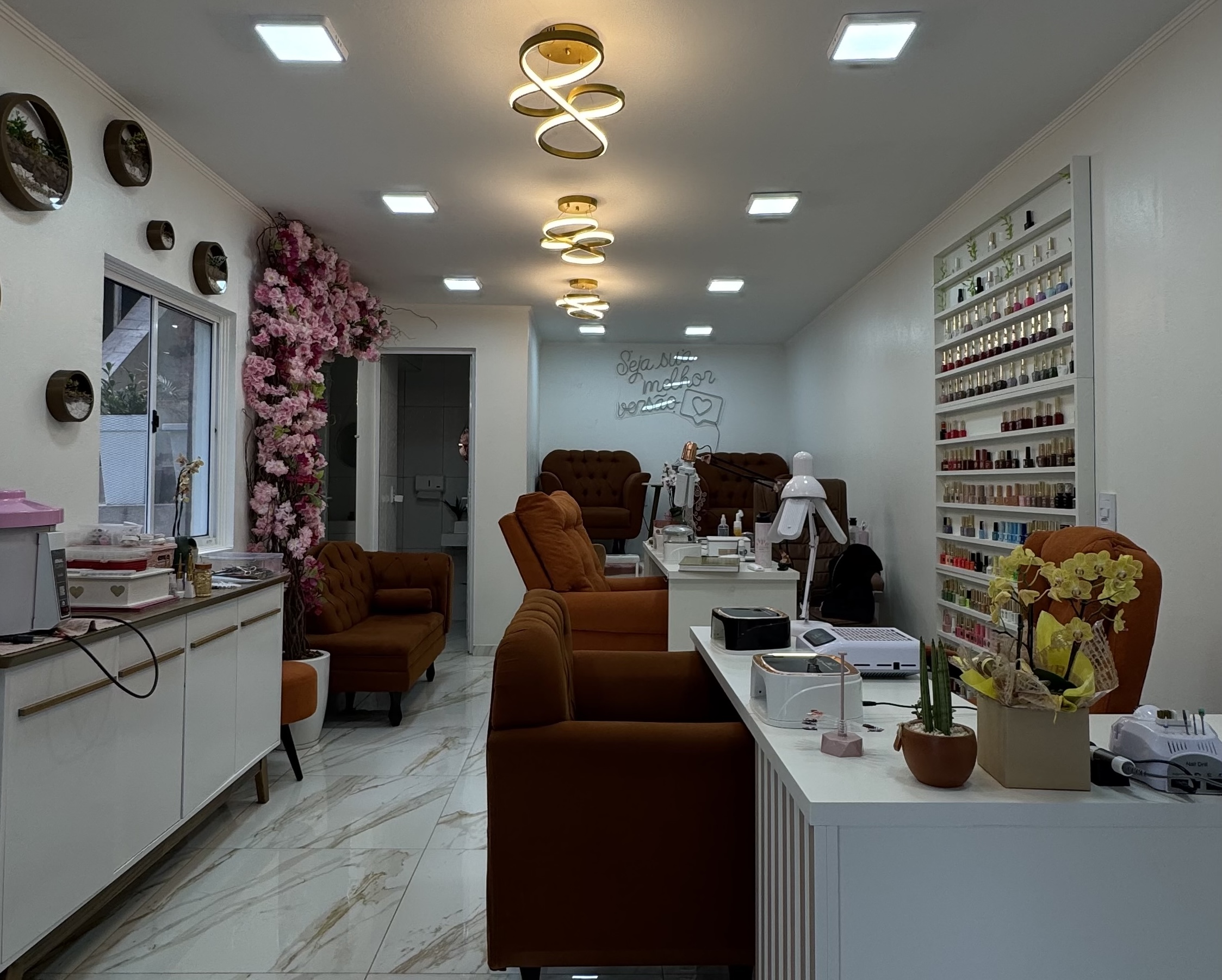 Interior do Studio Val Pinheiro — poltronas cognac, lustres dourados, piso de mármore