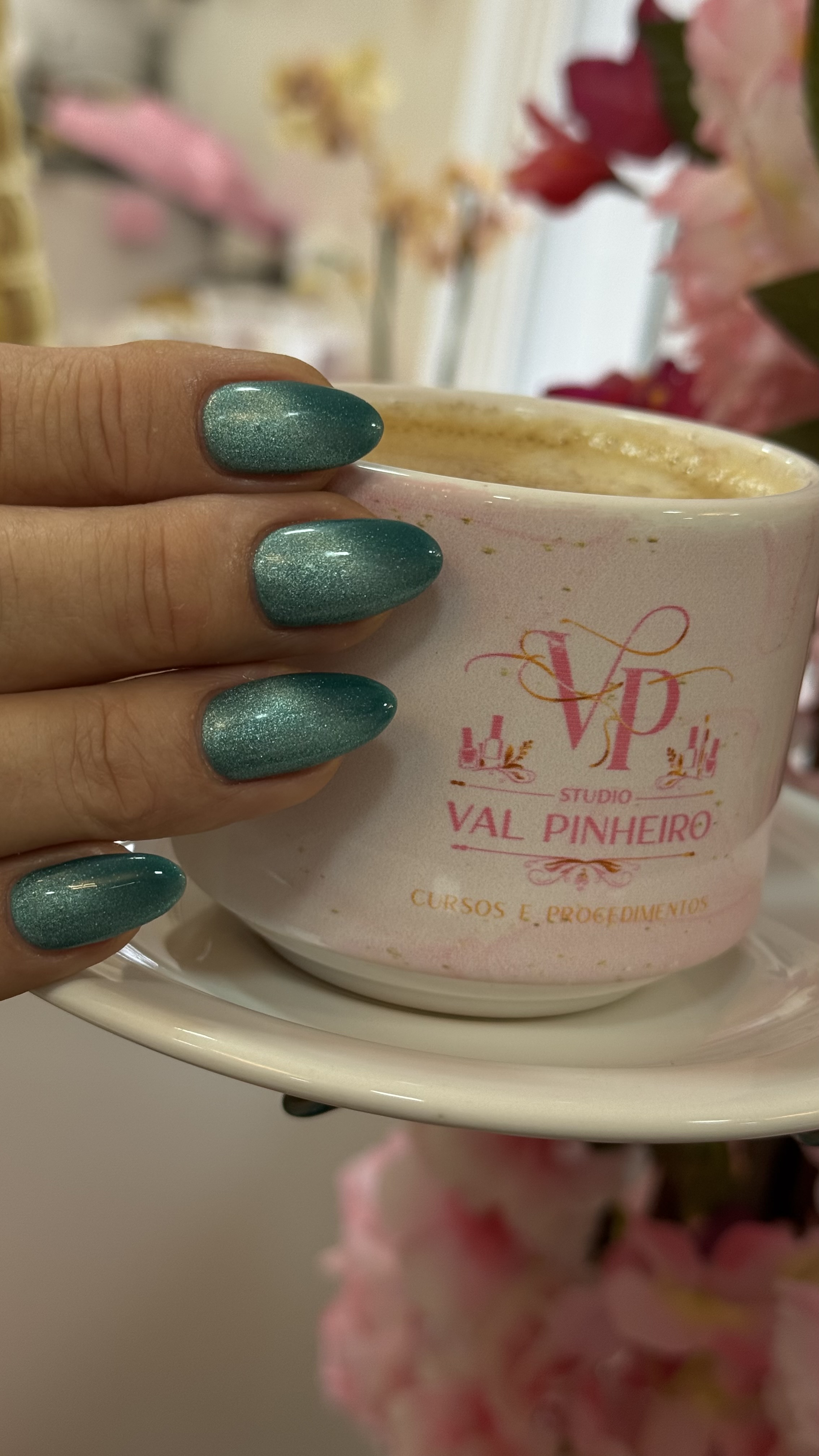 Unhas verde-esmeralda feitas no Studio Val Pinheiro segurando xícara personalizada